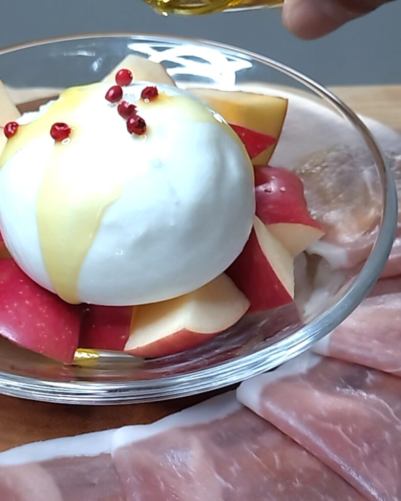 ブッラータにピンクペッパーとオリーブオイルをかける
